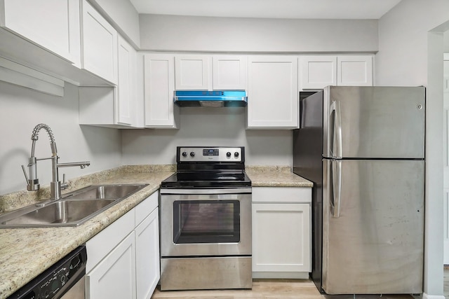 kitchen featuring sink, light stone countertops, white cabinets, light wood-type flooring, and appliances with stainless steel finishes