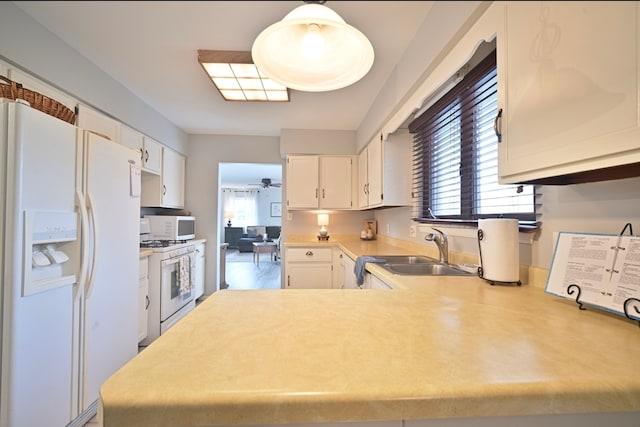 kitchen with white appliances, sink, hanging light fixtures, ceiling fan, and white cabinets