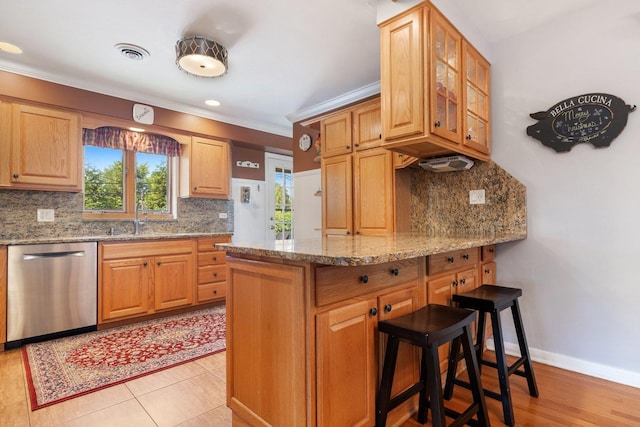 kitchen with dishwasher, crown molding, light stone countertops, sink, and tasteful backsplash