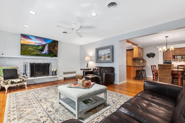 living room with radiator, ceiling fan with notable chandelier, and light wood-type flooring