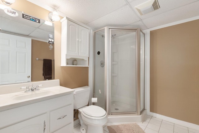 bathroom featuring a paneled ceiling, tile patterned flooring, toilet, and walk in shower