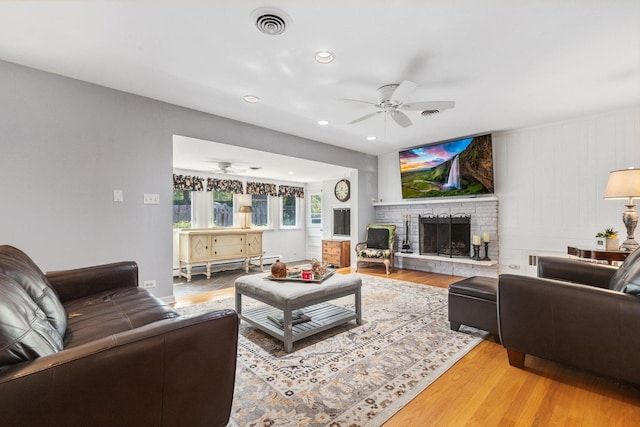 living room with wood-type flooring, a baseboard radiator, and ceiling fan