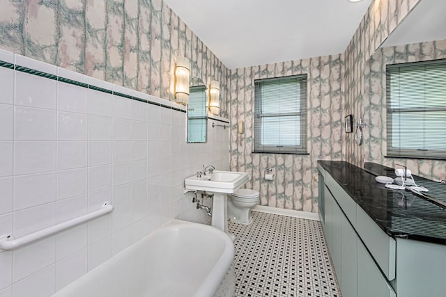 bathroom featuring a bathtub, toilet, tile walls, and sink