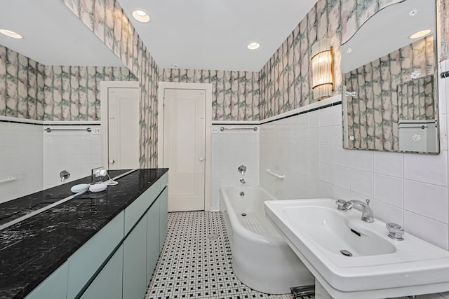 bathroom with vanity, tile walls, and a bath