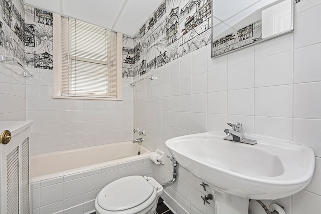 full bathroom featuring toilet, tiled shower / bath combo, and tile walls