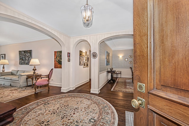 entrance foyer featuring an inviting chandelier, crown molding, and dark hardwood / wood-style flooring