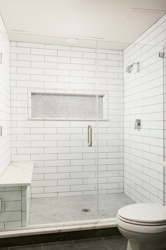 bathroom with a shower with door, tile patterned flooring, and toilet