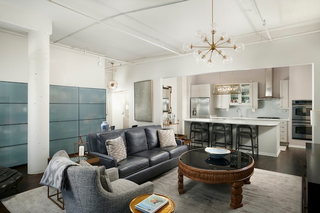 living room with a notable chandelier, wood-type flooring, and sink