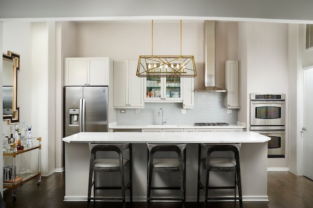 kitchen with a kitchen bar, dark hardwood / wood-style flooring, stainless steel appliances, and white cabinetry