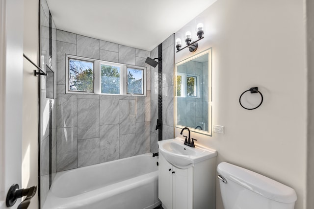 full bathroom featuring vanity, tiled shower / bath, and toilet