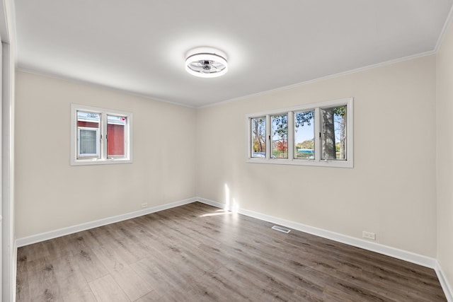 unfurnished room with crown molding, wood-type flooring, and plenty of natural light