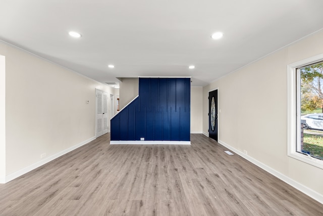 unfurnished living room featuring crown molding and light wood-type flooring