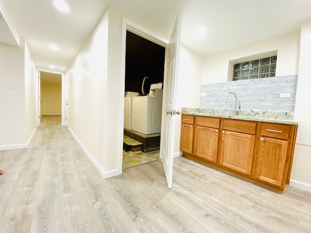 kitchen with sink, decorative backsplash, light hardwood / wood-style flooring, and washing machine and dryer