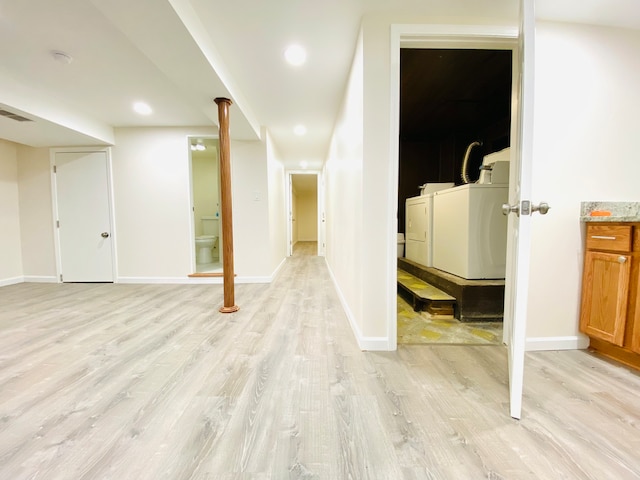 basement featuring washing machine and dryer and light wood-type flooring