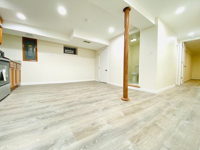 basement featuring light hardwood / wood-style flooring and electric panel