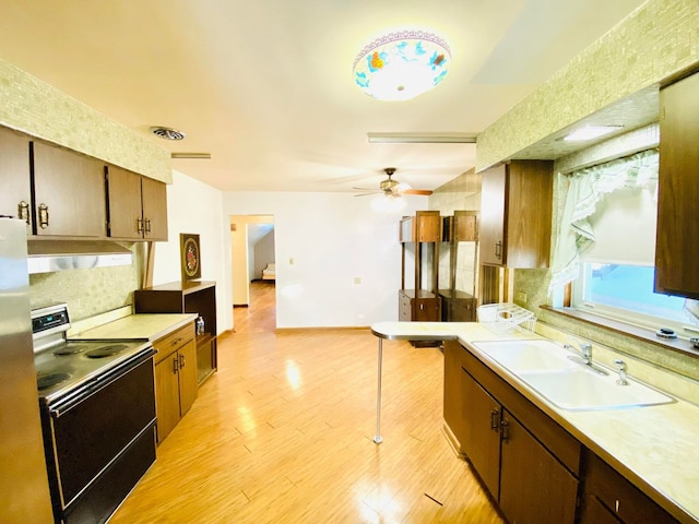 kitchen with sink, light wood-type flooring, decorative backsplash, ceiling fan, and range with electric stovetop