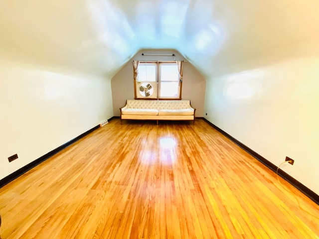 bonus room with vaulted ceiling and light wood-type flooring