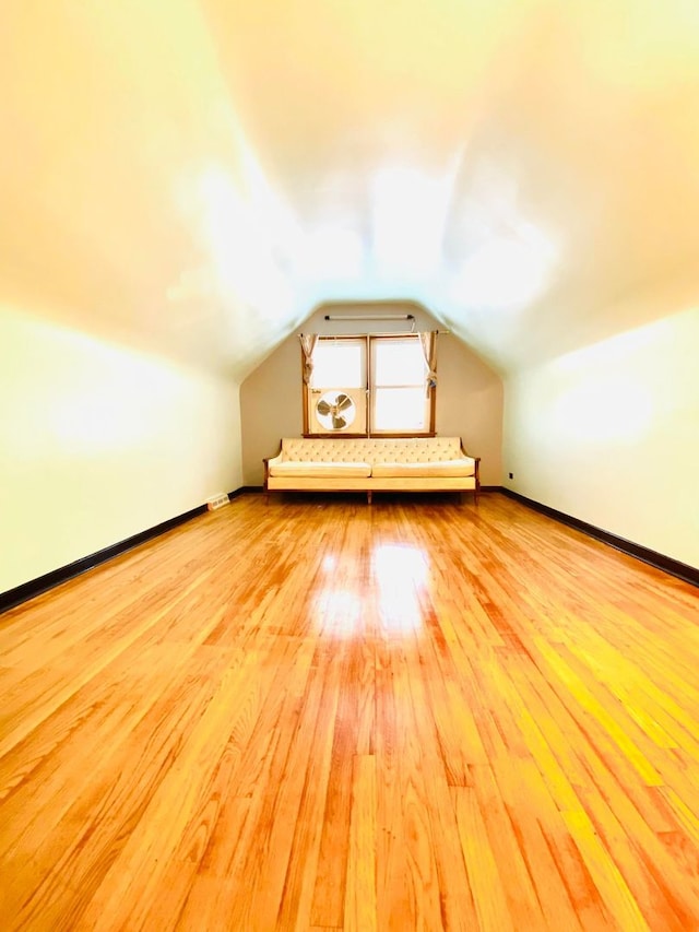 additional living space featuring vaulted ceiling and light wood-type flooring