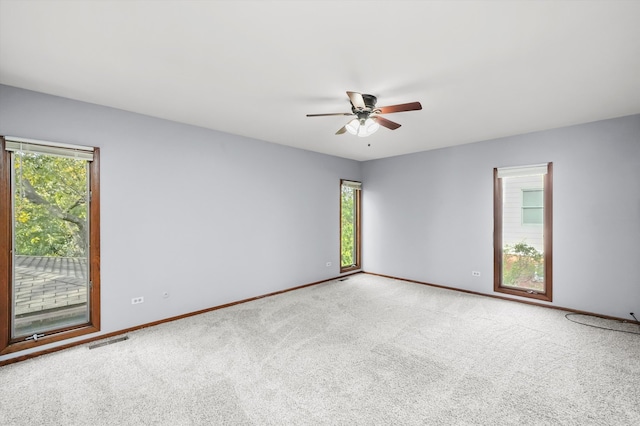 carpeted empty room with a healthy amount of sunlight and ceiling fan