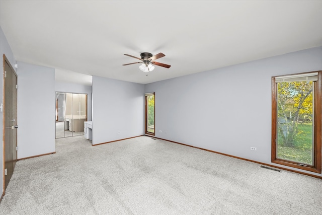 carpeted empty room featuring ceiling fan and a wealth of natural light