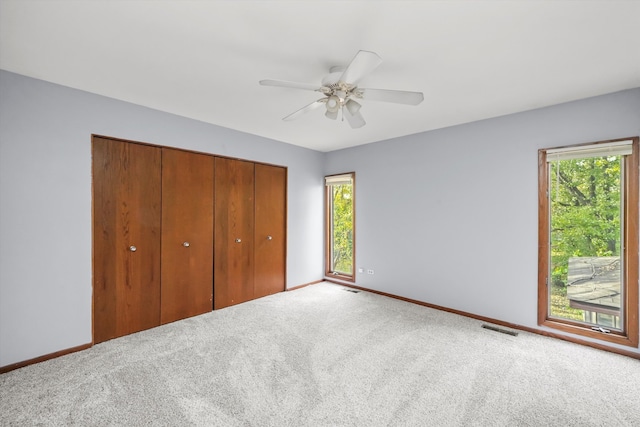 unfurnished bedroom with carpet flooring, multiple windows, and ceiling fan