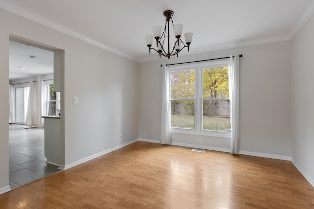 spare room featuring crown molding, a notable chandelier, and light wood-type flooring