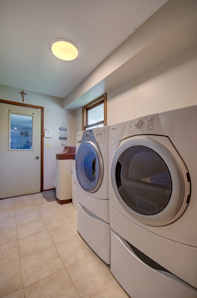 clothes washing area featuring washer and clothes dryer and light tile patterned floors