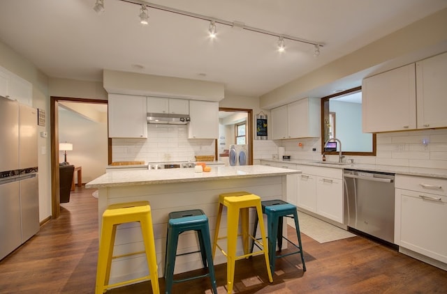 kitchen featuring white cabinets, a kitchen island, appliances with stainless steel finishes, a breakfast bar, and dark hardwood / wood-style floors