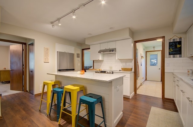 kitchen featuring dark hardwood / wood-style floors, a kitchen breakfast bar, a center island, white cabinets, and appliances with stainless steel finishes