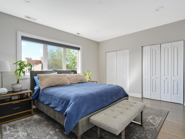 bedroom featuring dark hardwood / wood-style floors and multiple closets