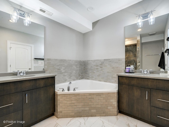 bathroom with vanity and tiled tub