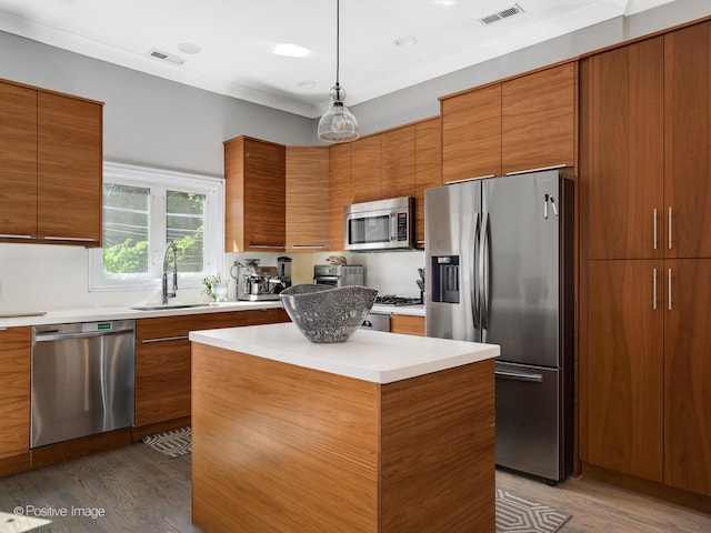 kitchen featuring sink, appliances with stainless steel finishes, decorative light fixtures, a kitchen island, and dark hardwood / wood-style flooring