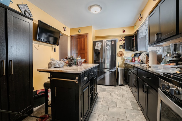 kitchen featuring stainless steel appliances, light stone countertops, a center island, and a kitchen bar