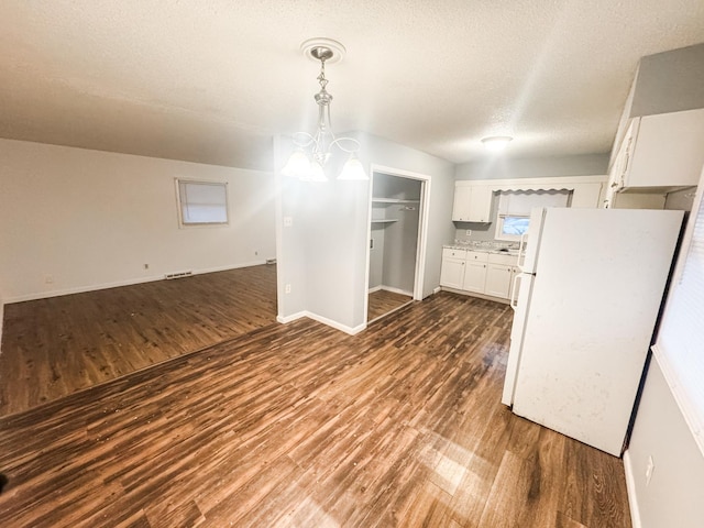 unfurnished dining area featuring a chandelier, a textured ceiling, and dark hardwood / wood-style flooring