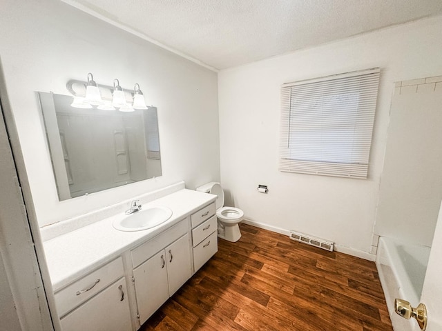 bathroom featuring hardwood / wood-style flooring, vanity, a textured ceiling, a tub to relax in, and toilet