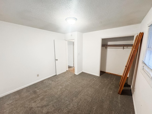 unfurnished bedroom featuring a textured ceiling, dark carpet, and a closet