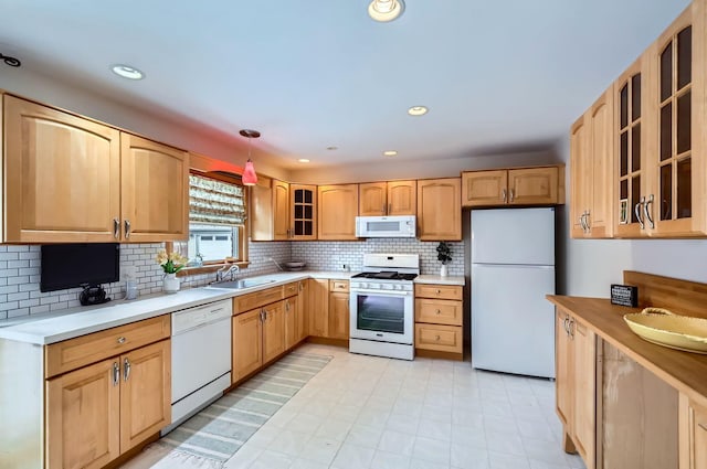 kitchen with white appliances, decorative light fixtures, sink, and light brown cabinets