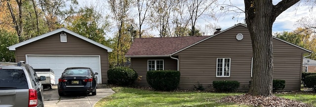 single story home featuring a garage, an outbuilding, and a front lawn