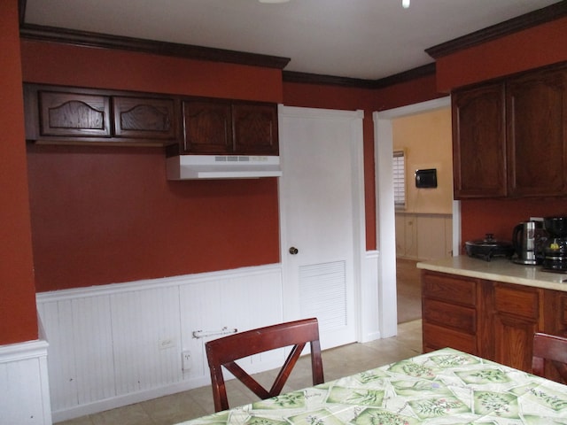 kitchen with light tile patterned floors, dark brown cabinets, and crown molding