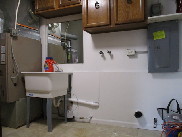 clothes washing area featuring hookup for a washing machine, cabinets, sink, and electric panel