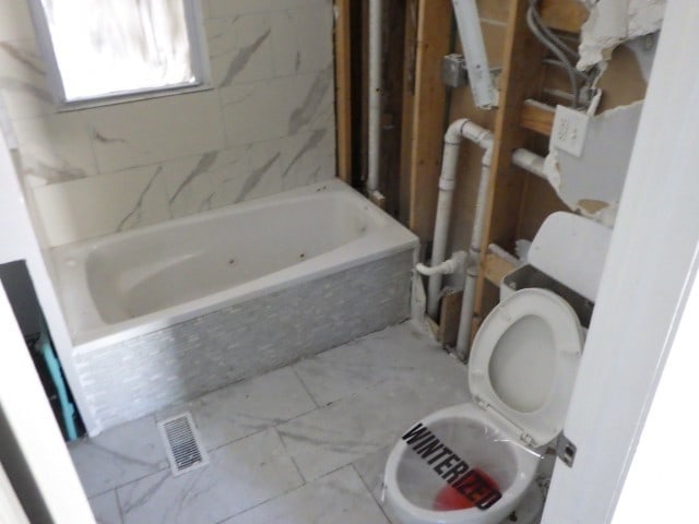 bathroom featuring toilet and tiled tub