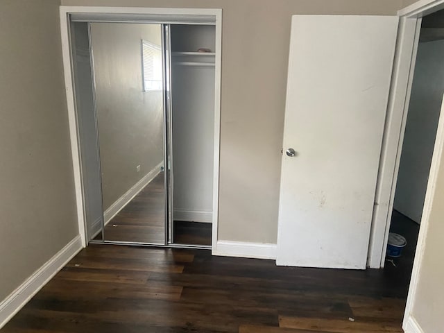 unfurnished bedroom featuring dark hardwood / wood-style flooring and a closet