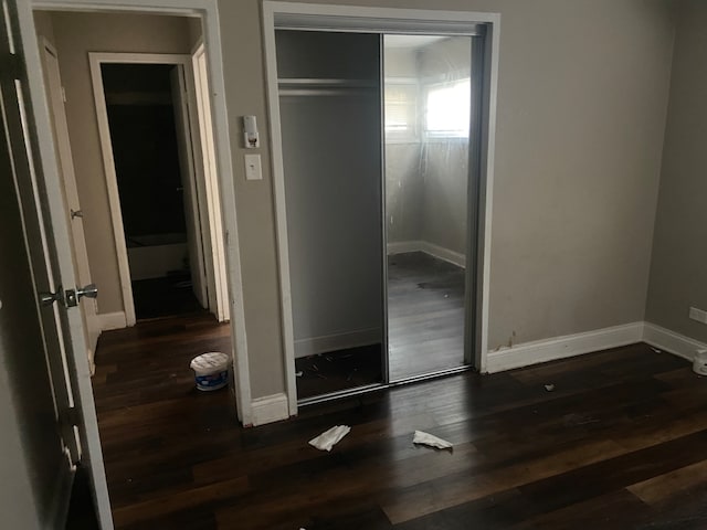 unfurnished bedroom with dark hardwood / wood-style flooring and a closet