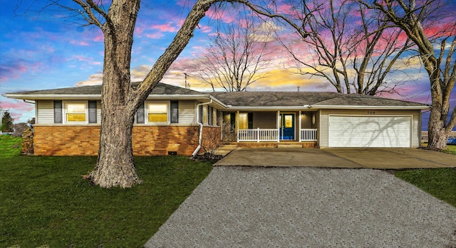 ranch-style house with covered porch, a garage, and a lawn