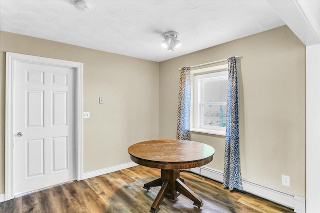 dining room featuring a baseboard heating unit and hardwood / wood-style floors