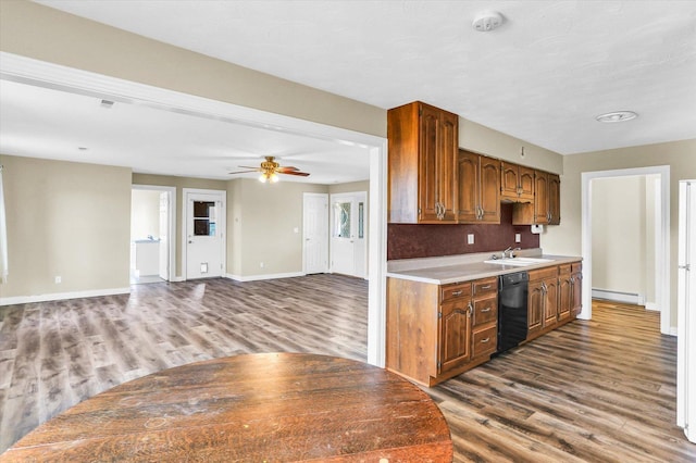 kitchen featuring sink, black dishwasher, a baseboard heating unit, ceiling fan, and dark hardwood / wood-style flooring