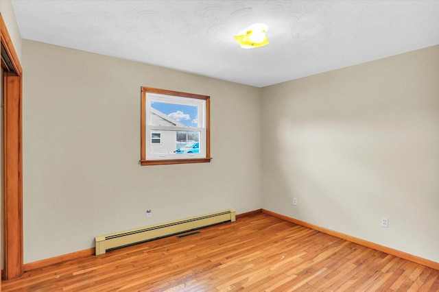 unfurnished room featuring a baseboard radiator and light hardwood / wood-style flooring