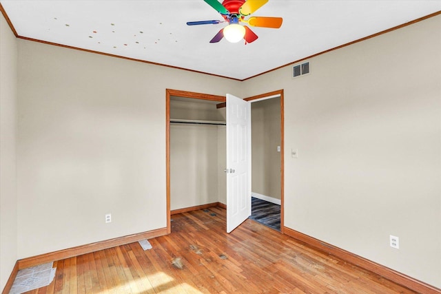 unfurnished bedroom with ornamental molding, hardwood / wood-style flooring, ceiling fan, and a closet