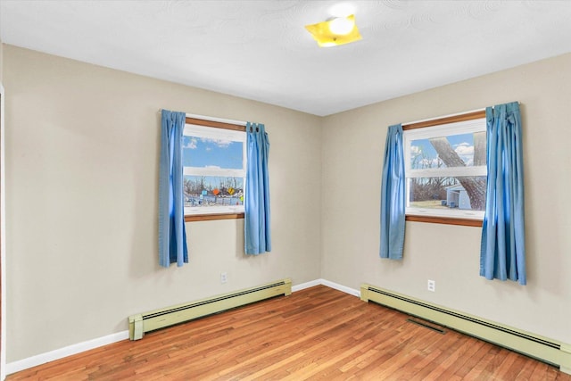 unfurnished room featuring plenty of natural light, wood-type flooring, and a baseboard radiator