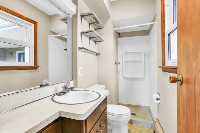 bathroom featuring toilet, a baseboard heating unit, vanity, and walk in shower